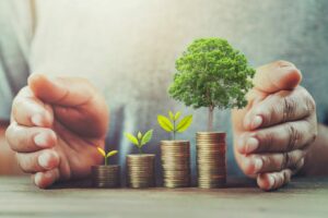 businessman protection money on table with tree. concept saving stacks of money with trees growing on top of them to represent energy saving tips for businesses