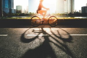 A young women going to work place by her bike in morning. Woman riding a bike near a river
