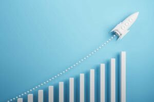 Startup and new project concept with white rocket flying up with dotted trajectory above light growth graph on blue background. 3D rendering Startup and new project concept with white rocket flying up with dotted trajectory above light growth graph on blue background. showing the rise in energy despite the energy price cap