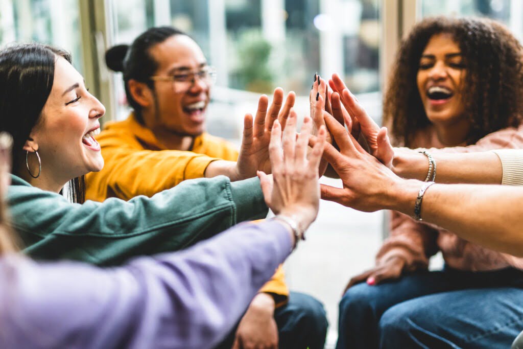 Multiracial happy young people stacking hands