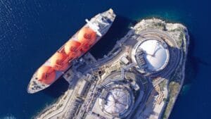 Aerial drone top down photo of LNG (Liquified Natural Gas) tanker anchored in small gas terminal island with tanks for storage to store and regasify LNG AdobeStock 555477711