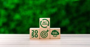 Wooden Blocks Displaying Net Zero, CO2 Emission Reduction, and 2050 Target Goals Against Green Background, Representing Climate Action and Sustainability Milestones UK clean energy by 2050 wooden blocks against a wall of bushes