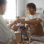 Effective Waste Solutions for the Hospitality Sector 2 Man paying barista with mobile phone in bakery while holding coffee representing hospitality