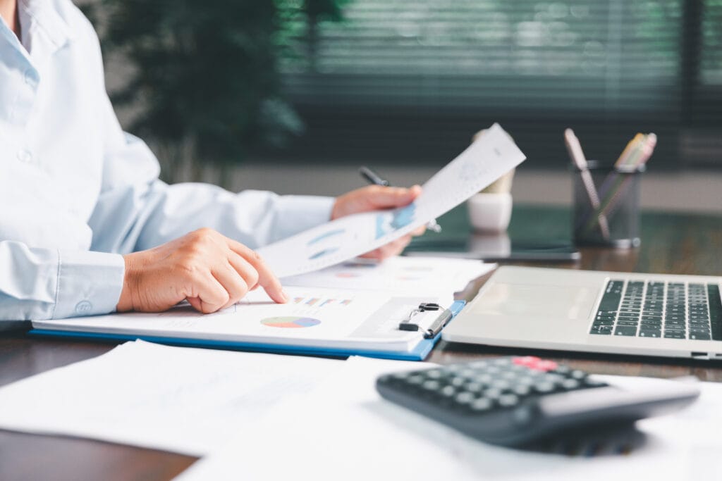 Office businesswoman hand to operate calculator analyzing financial data, counting costs on desk. accounting, financial analysis for business budget planning, calculation support, finance management. bills and calculator in office representing supplier billing issues