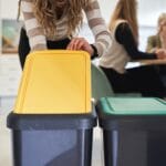 10 Smart Waste Management Tips to Help Your Business Save Money 1 Woman recycling waste in office kitchen with color-coded bins representing waste management