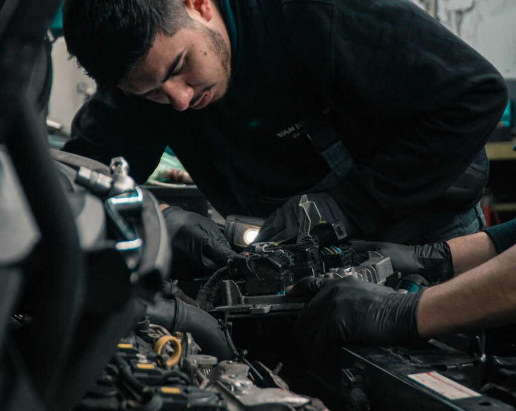 sten-rademaker-UZUzvJEvKnI-unsplash mechanic leaning over engine in car garage representing motor dealers