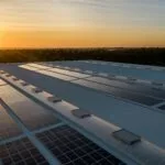Solar panels on a building rooftop at sunset representing renewables