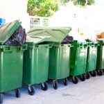 Are You Overpaying For Waste Management? 1 Row of green rubbish bins outdoors representing waste management