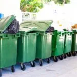 Row of green rubbish bins outdoors representing waste management
