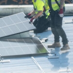 What Most Businesses Get Wrong About Solar 1 Two technicians placing solar panel on metal roof in bright daylight