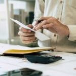 Electricity VAT Cut: What It Means for Businesses 1 man with receipt and pen surrounded by calculator etc representing VAT check