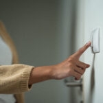 close up of woman turning off light switch representing business energy saving tips