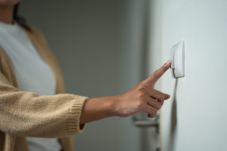 close up of woman turning off light switch representing business energy saving tips